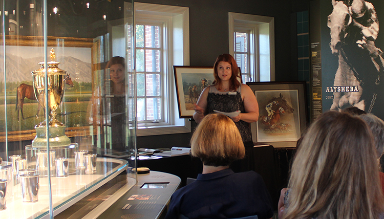 Jenni presents to a gathering at a museum exhibit Jenni presents to a gathering at a museum exhibit