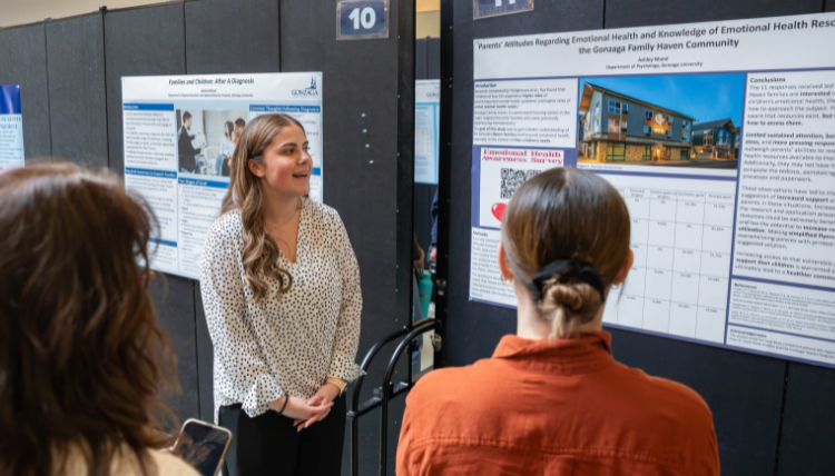 dsj-presentation-2026 A woman smiles at another as she presents her poster that is attached to a poster board