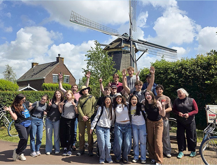 Many students and their teachers gather in front of a large windmill