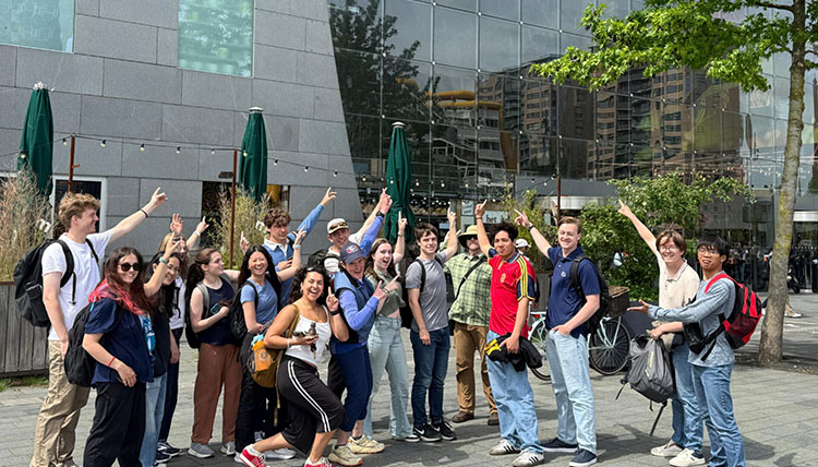 students point to a wall of glass panels