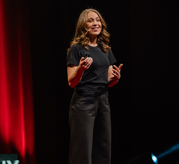 Female in black tshirt speaking on TedX stage
