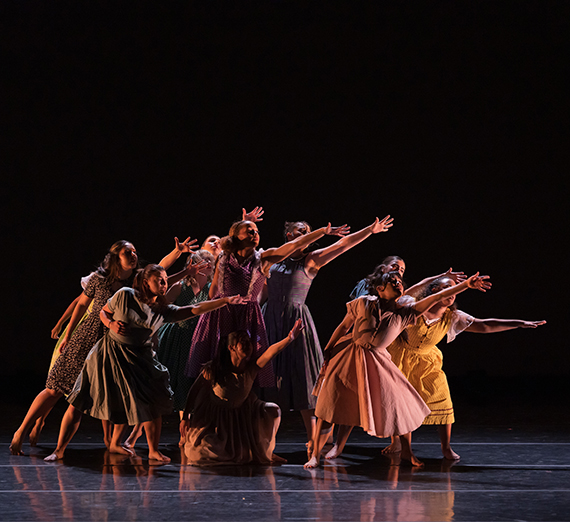 A group of dancers on stage huddled closely