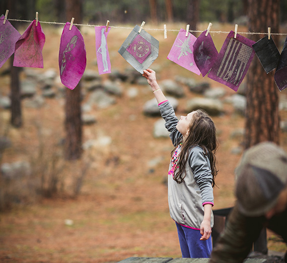 Young child reaching for paper artwork.