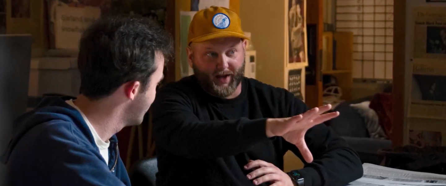 Zack Bagdon talking and gesturing with another person who is facing away from the camera. 