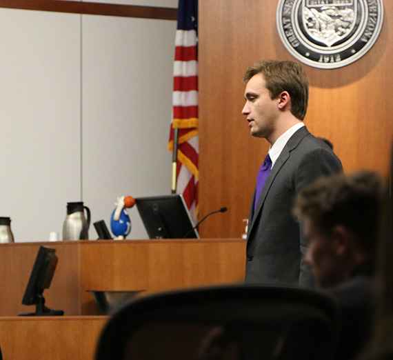 Luke Pfister stands in front of a mock trial court room. Luke Pfister stands in front of a mock trial court room.