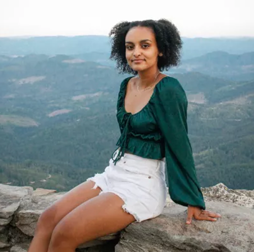 Mieri Kahsay sitting on a rock wall outside Mieri Kahsay sitting on a rock wall outside