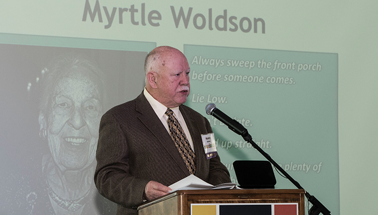 Monty Danner at podium with photo of Miss Woldson on screen behind Monty Danner at podium with photo of Miss Woldson on screen behind