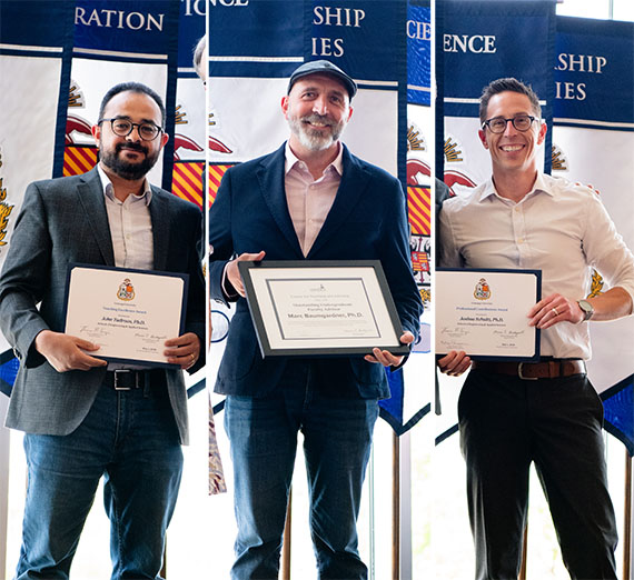 Three men stand with certificates