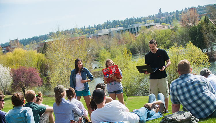 People gather informally by a pond to listen to poetry People gather informally by a pond to listen to poetry