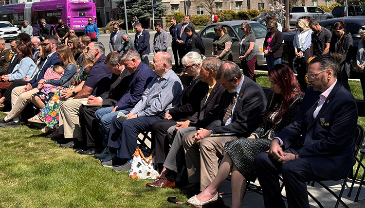 People sitting a row bow their heads in prayer.