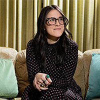 Leah sits on a couch with teal pillows. Leah sits on a couch with teal pillows.