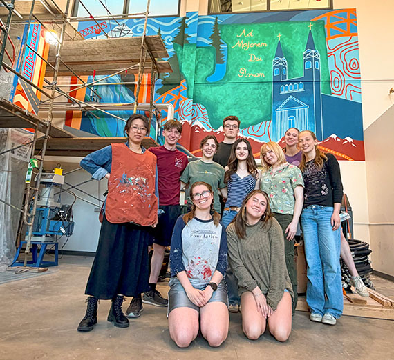 students group wtih a professor in front of a mural surrounded by scaffolding