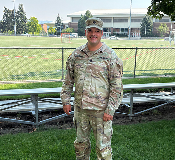 A man in military uniform standing in front of metal bleachers outside