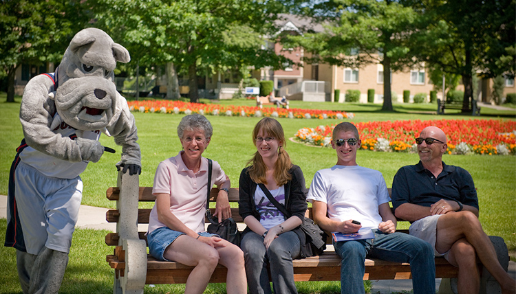 A Gonzaga family sitting on a bench on campus with GU's mascot, Spike A Gonzaga family sitting on a bench on campus with GU's mascot, Spike