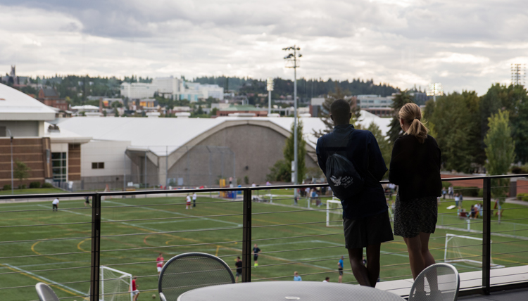 Two GU students stand on Hemmingson balcony overlooking mulligan turf field Two GU students stand on Hemmingson balcony overlooking mulligan turf field