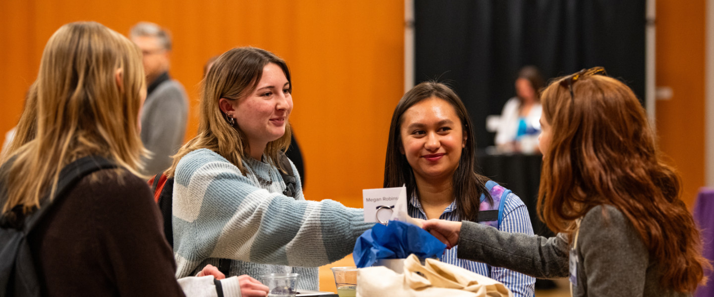 Students talking and shaking hands at a networking event.