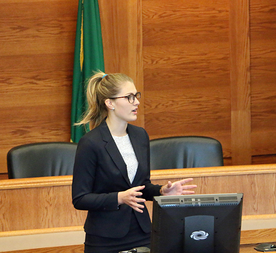 Maggie Kruzner stands in front of a mock trial court room. Maggie Kruzner stands in front of a mock trial court room.