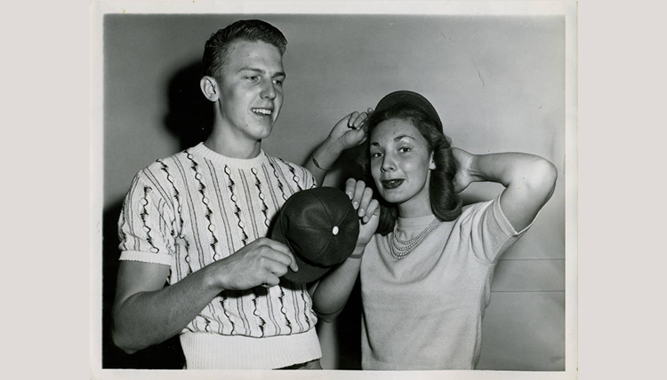 black and white image of male and female students trying on beanies black and white image of male and female students trying on beanies