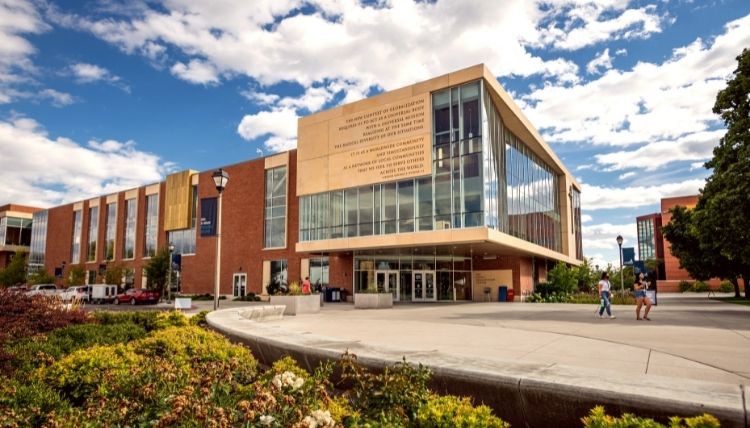 A shot of the main entrance of Hemmingson Center. A couple students are walking nearby. A shot of the main entrance of Hemmingson Center. A couple students are walking nearby.