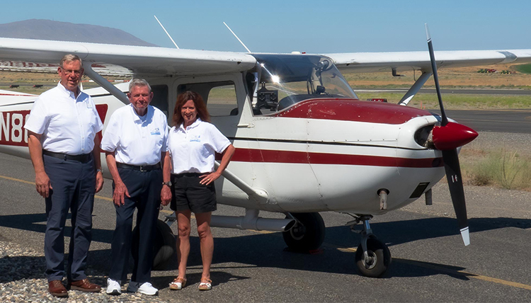 three people in front of a small airplace