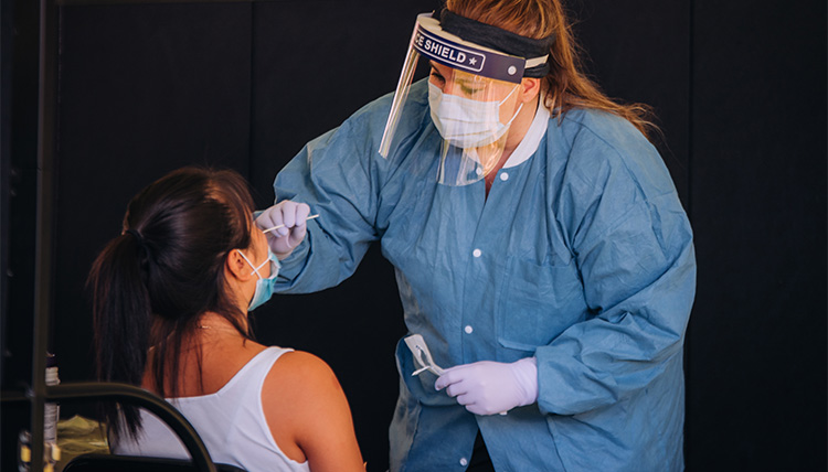 A student is tested for covid-19 by a nurse wearing personal protective equipment. A student is tested for covid-19 by a nurse wearing personal protective equipment.