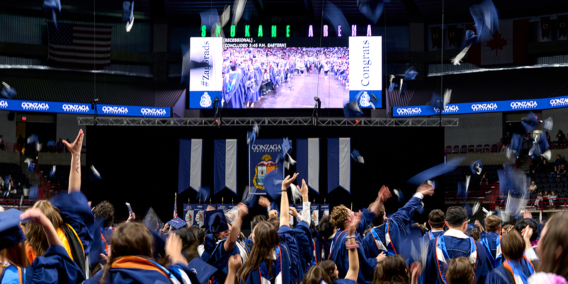 Students celebrate commencement ceremony in an arena.