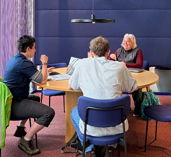 Three people at a round table looking at laptops