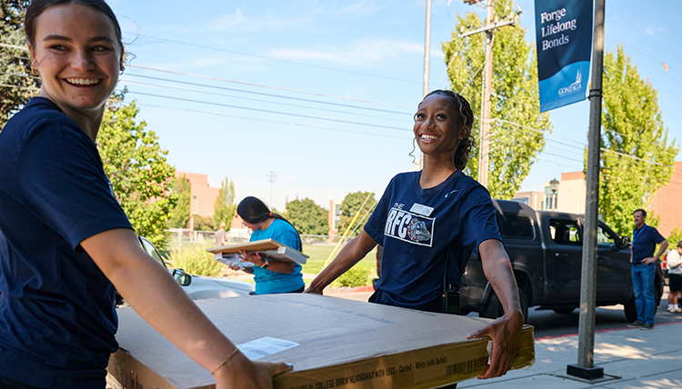 two women carry a table