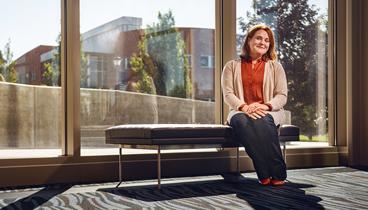 woman sits on bench in campus building