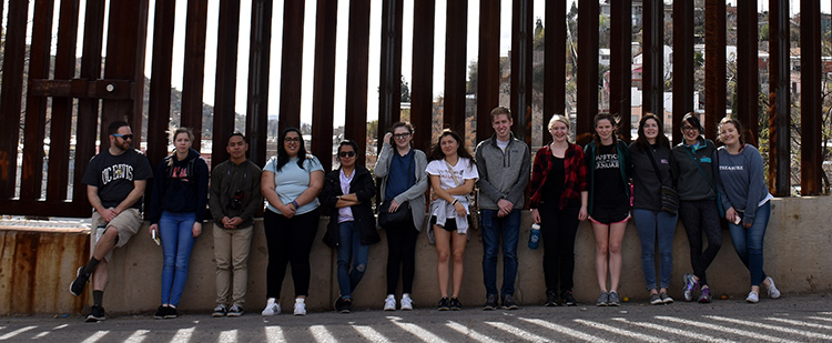 Students stand for a picture in front of the border wall near Nogales Students stand for a picture in front of the border wall near Nogales
