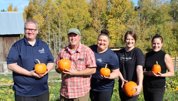 A group of people holding pumpkins and smiling A group of people holding pumpkins and smiling