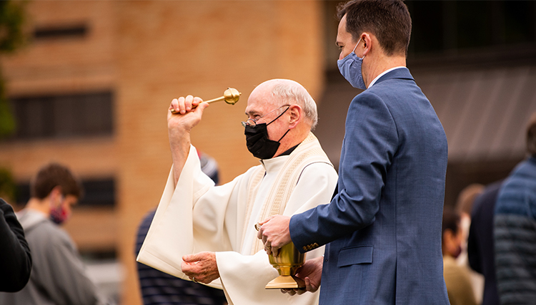 Jesuit priest blessings attendees at commencement Mass Jesuit priest blessings attendees at commencement Mass