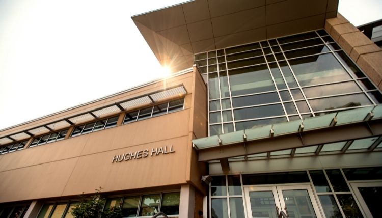 A shot of the front of Hughes Hall, taken looking upward. The sun is peeking out behind the bulding. A shot of the front of Hughes Hall, taken looking upward. The sun is peeking out behind the bulding.
