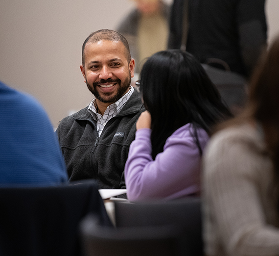 A smiling man at a table of coworkers