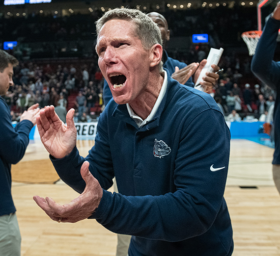 A man in Gonzaga sweatshirt clapping his hands