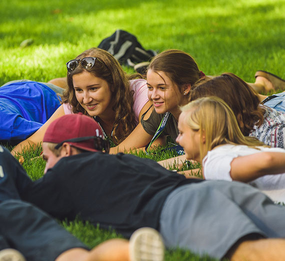 Students laying on grass playing games Students laying on grass playing games
