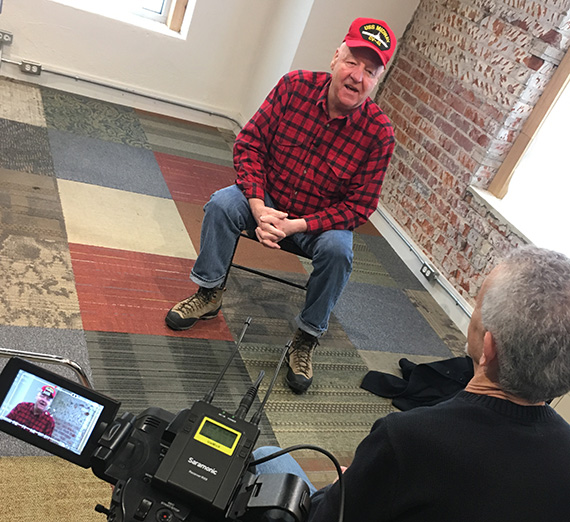 Person being interviewed in front of video camera. Decorative image