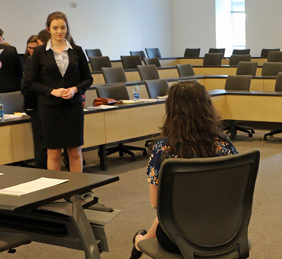 Hillary Longoria stands in front of a mock trial court room. Hillary Longoria stands in front of a mock trial court room.