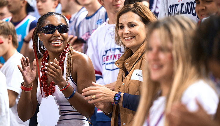 A woman in sunglasses claps in the crowd of a basketball game A woman in sunglasses claps in the crowd of a basketball game