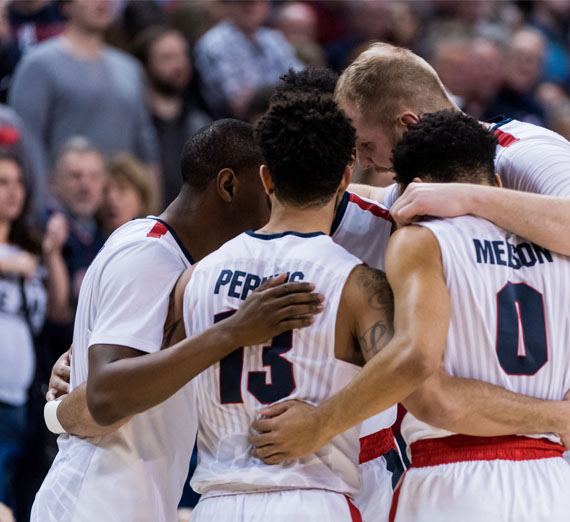 mens basketball team huddles at game 