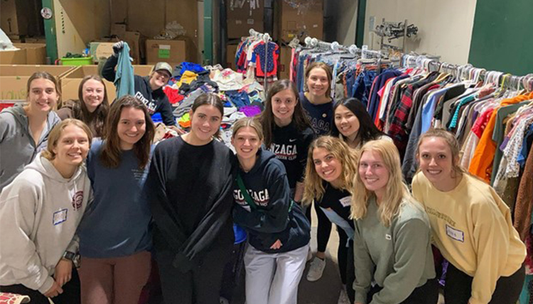 13 Gonzaga Students pose for a photo at the Global Neighborhood thrift clothes sorting room. 13 Gonzaga Students pose for a photo at the Global Neighborhood thrift clothes sorting room.