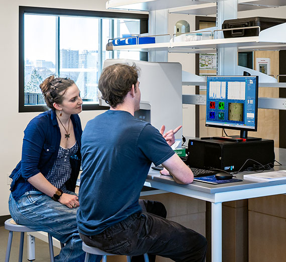 College students refer to a screen displaying test results in an engineering lab College students refer to a screen displaying test results in an engineering lab