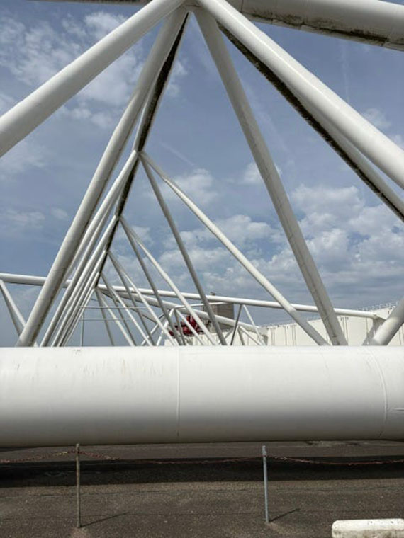 Large white metal poles criscross in a triangular shape