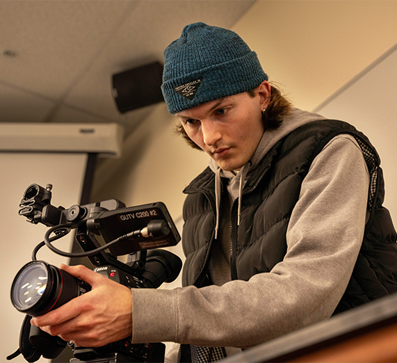 A student filming with a video camera.