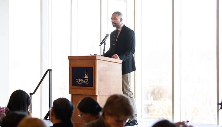 A man at a podium speaks to a room full of people