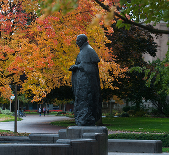 A statue of Saint Ignatius with orange leaves in background