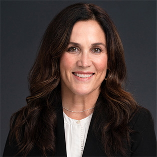 Woman smiles at camera with a simple background.