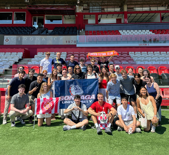 Group photo picture holding up a Gonzaga flag with a bulldog on it. 
