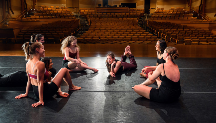 Dancers on stage seated together chatting Dancers on stage seated together chatting
