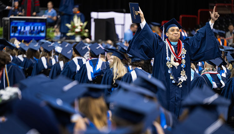 A graduate raises his arms with joy after receiving his degree A graduate raises his arms with joy after receiving his degree